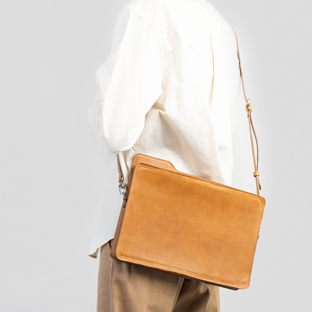 Tan leather bag with adjustable shoulder strap inspired by Apple OS folder silhouette worn crossbody