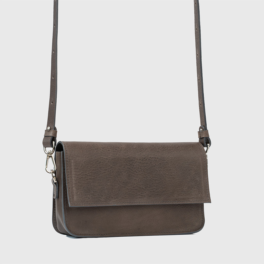 Gray leather shoulder bag with adjustable strap and flap closure, stylish and functional design
