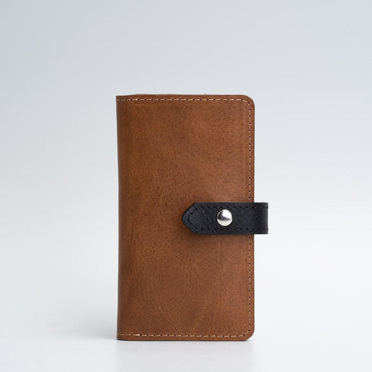 Brown leather folio wallet with black snap button strap and MagSafe 2.0 compatibility, handcrafted from premium vegetable-tanned leather