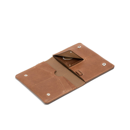 Brown leather AirTag travel wallet with multiple card slots and snap button closures, designed to securely hold passport, cards, and cash.