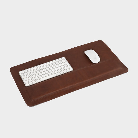 Brown premium leather desk mat with padded wrist support, keyboard, and mouse on top