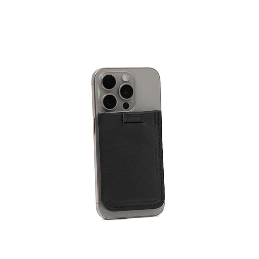 Black leather MagSafe wallet attached to the back of an iPhone, designed to hold 4-6 cards with premium full-grain Italian leather and strong magnet compatibility.