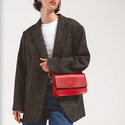Woman wearing a red leather shoulder bag with a gray plaid blazer and white shirt