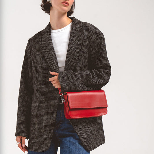 Woman wearing a red leather shoulder bag with a gray plaid blazer and white shirt