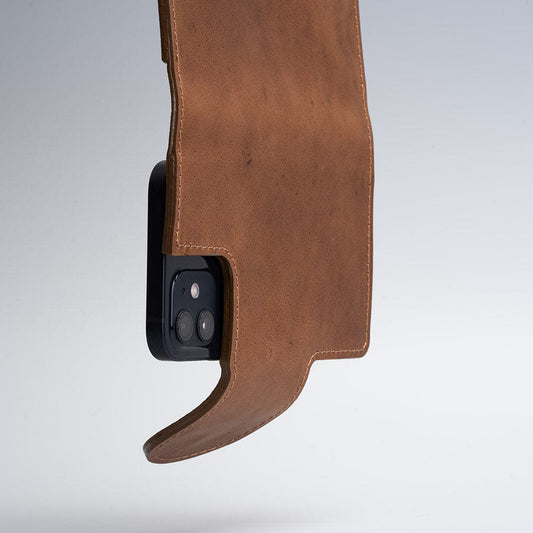Brown leather folio wallet with MagSafe compatibility and magnetic closure hanging open on a smartphone